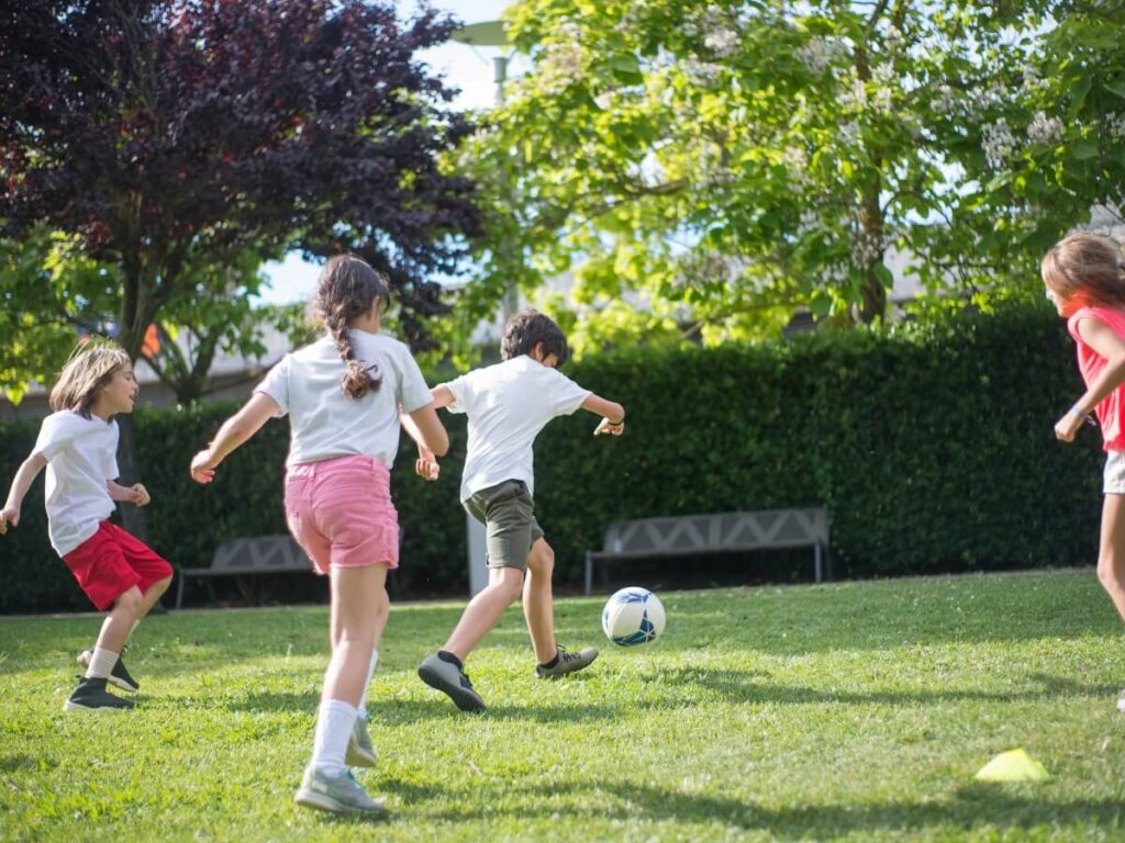 Kids Playing Soccer On A Lawn
